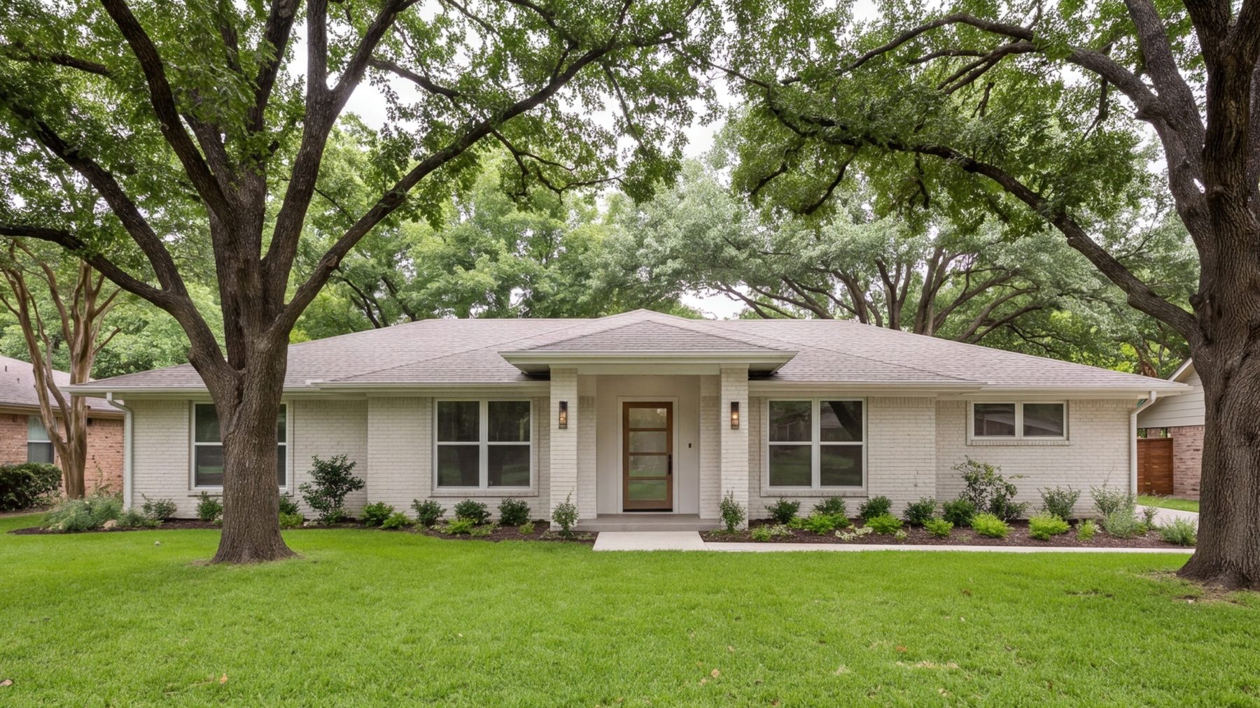 Street view of a remodeled 1960s brick ranch house in Fort Worth with a new entry and mature trees